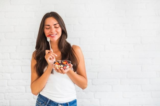 Smiling woman holding a bowl of salad, representing healthy eating for managing blood pressure