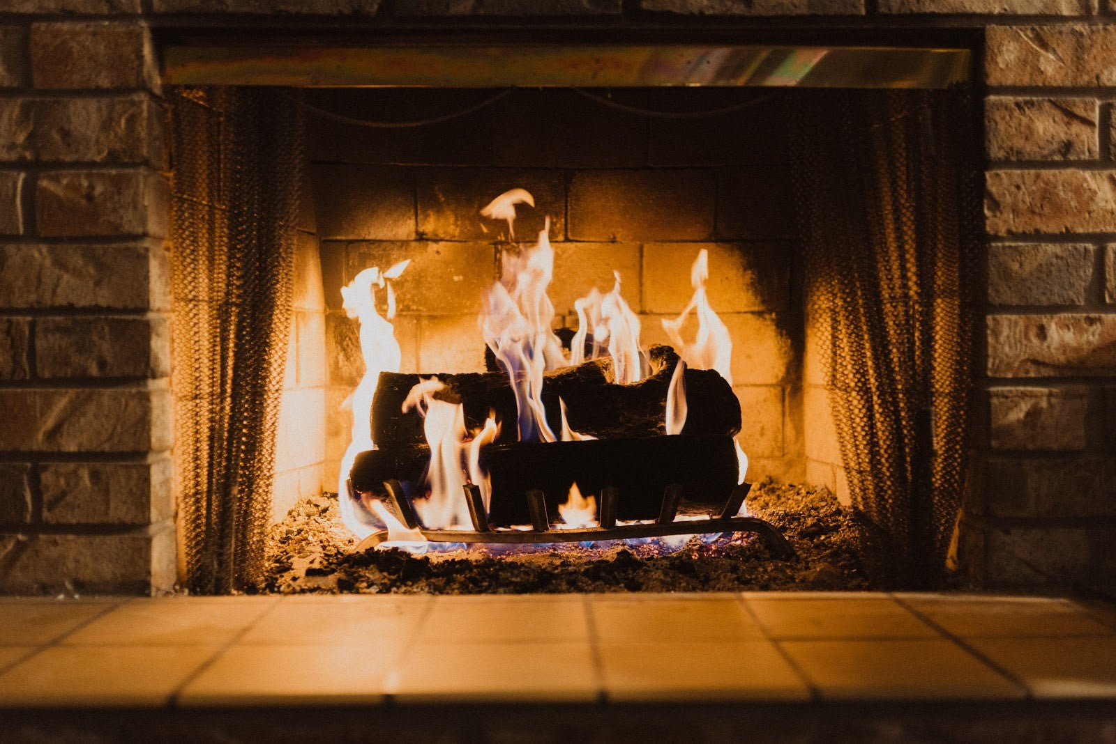 Burning fireplace with visible flames inside a stone mantel, potentially releasing smoke and indoor air pollutants.
