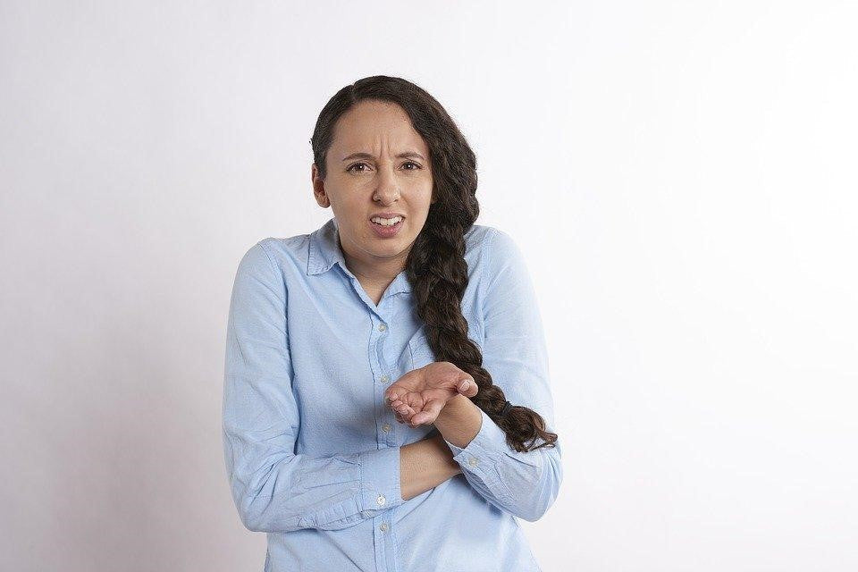 Concerned woman in blue shirt clutching chest, representing difficulty breathing or asthma-related discomfort.