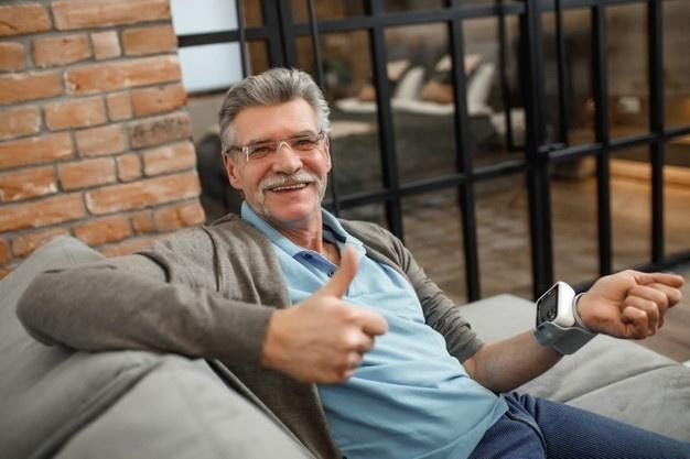Man sitting down on couch wearing blood pressure monitor
