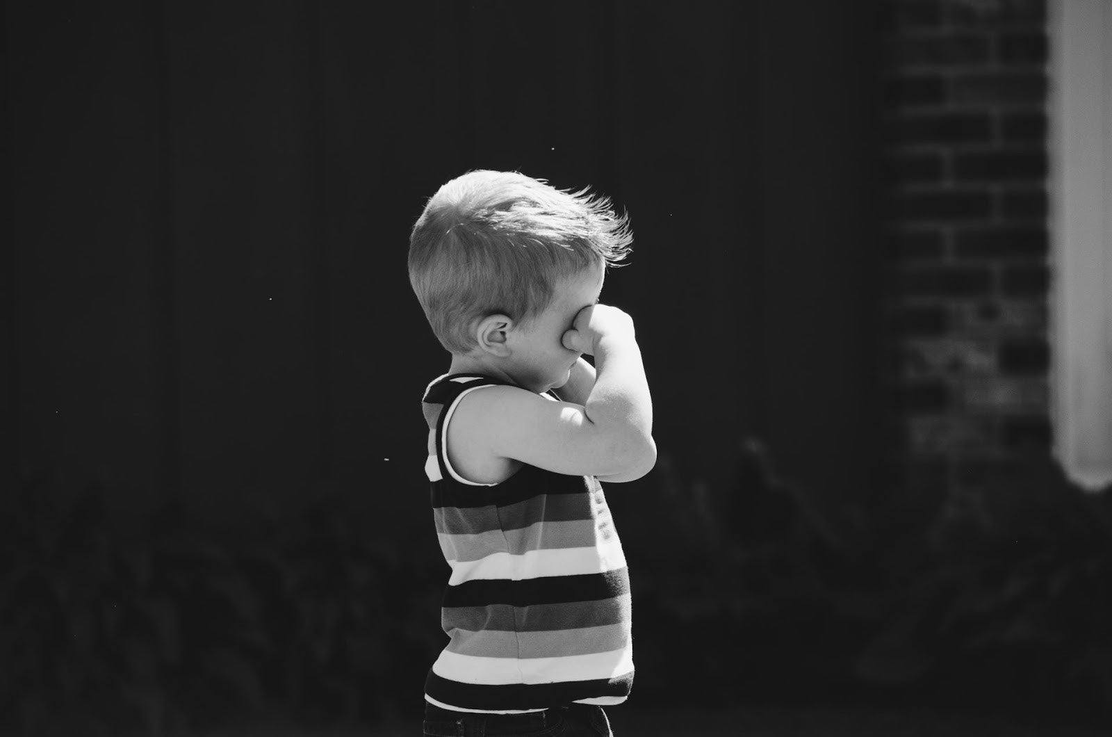 "Young boy holding his nose, possibly experiencing breathing difficulty related to asthma"