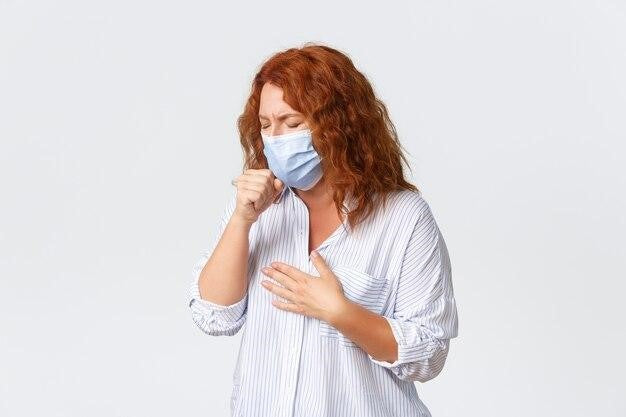 Woman coughing into tissue while wearing a medical face mask