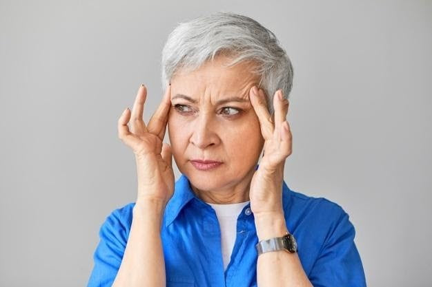 Senior woman looking worried with hands on temples, symbolizing stress or concern over blood pressure