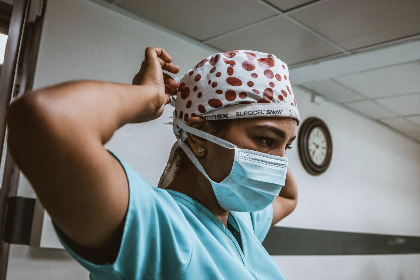 Healthcare worker putting on protective face mask and head covering—representing medical preparedness and infection prevention