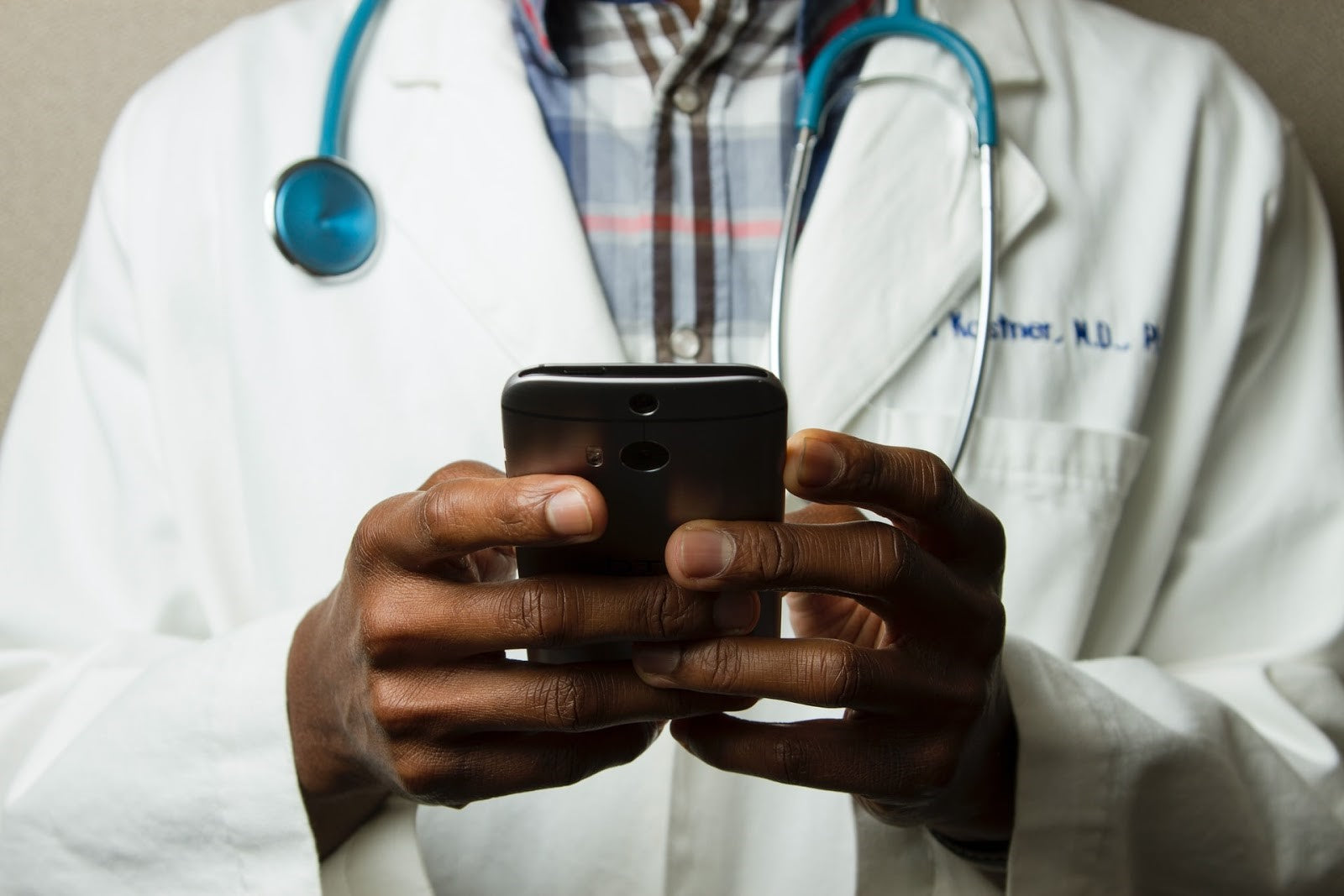 Doctor in white coat using smartphone, symbolizing telemedicine, healthcare apps, or digital health tools