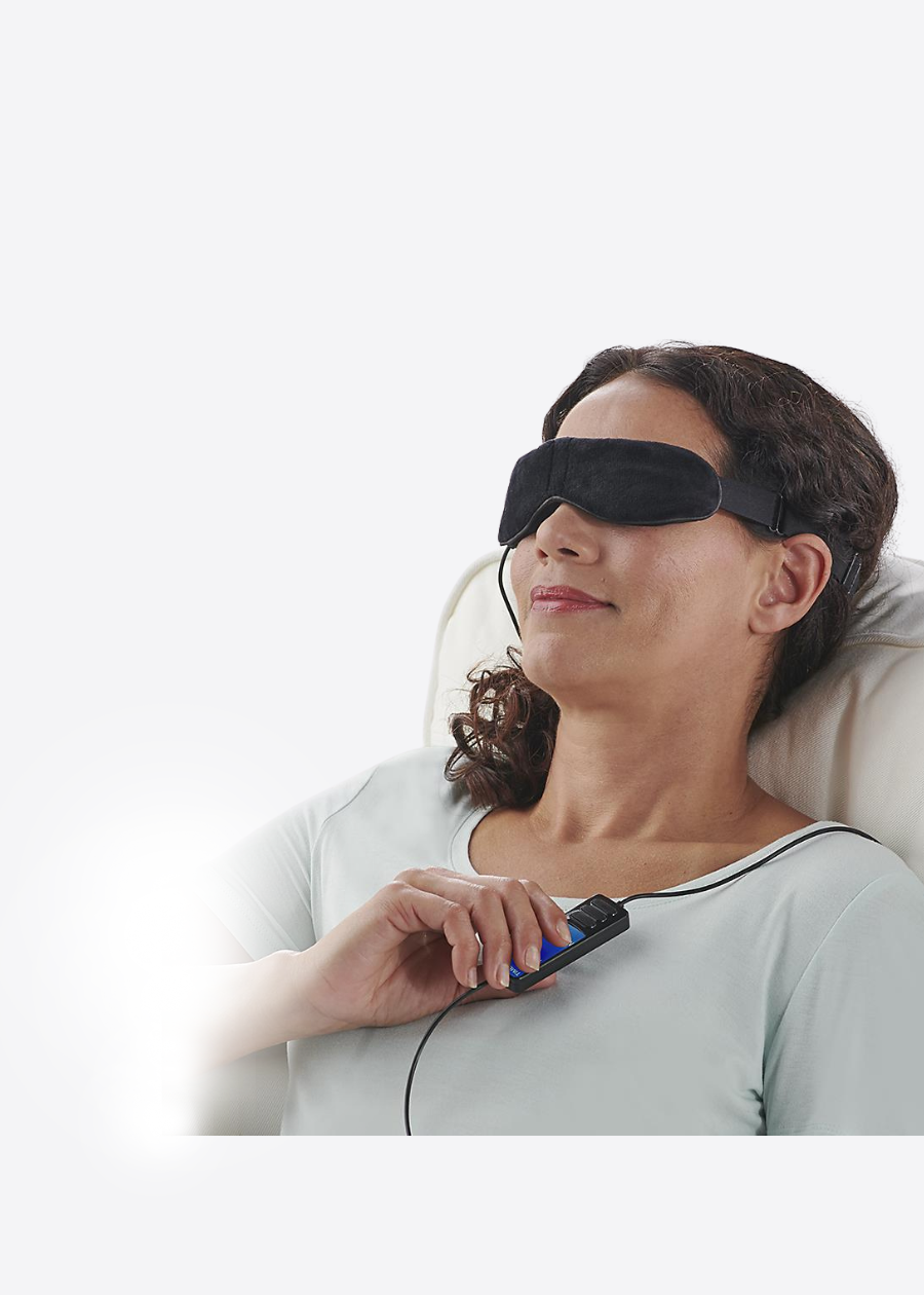 smiling woman wearing heated eye mask holding controller on grey background