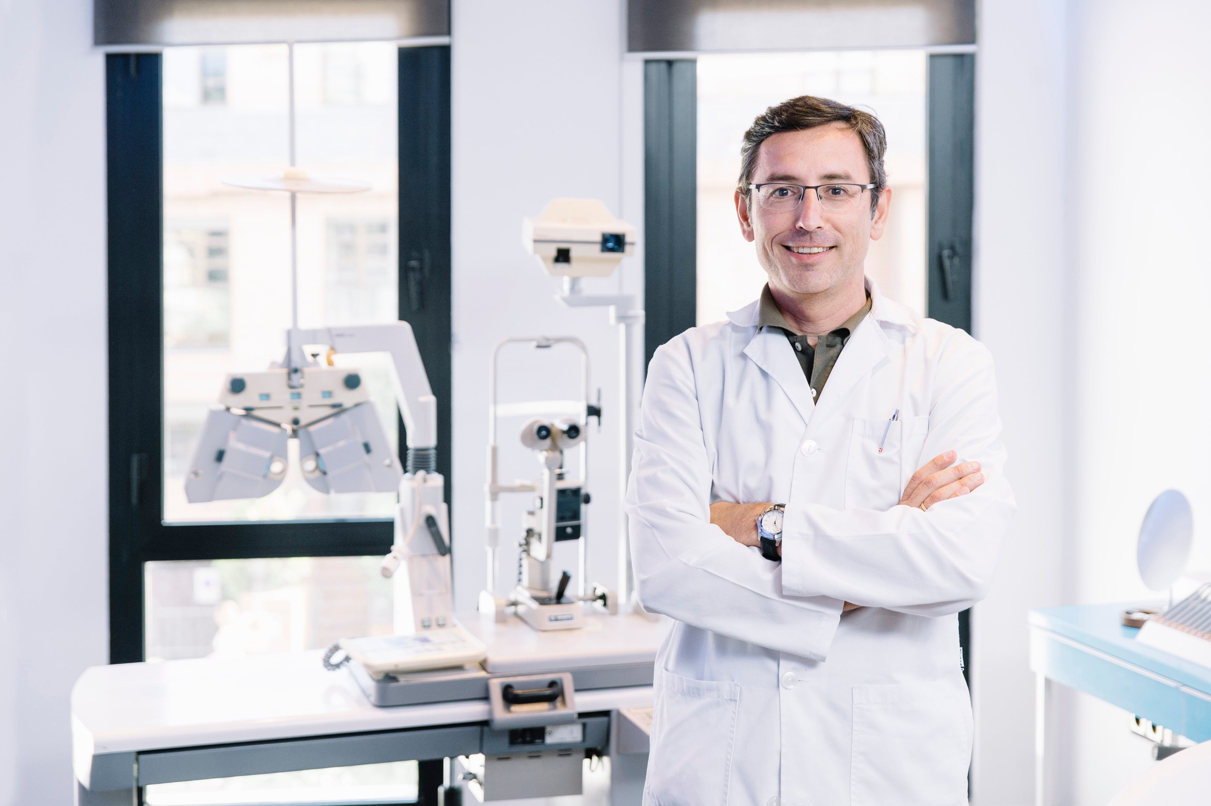 Eye doctor in lab coat standing in modern optometry clinic
