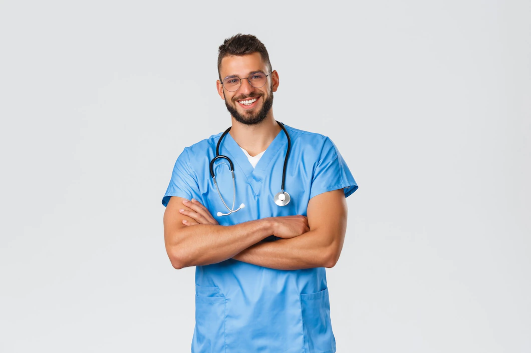 Smiling doctor in blue scrubs with stethoscope on white background
